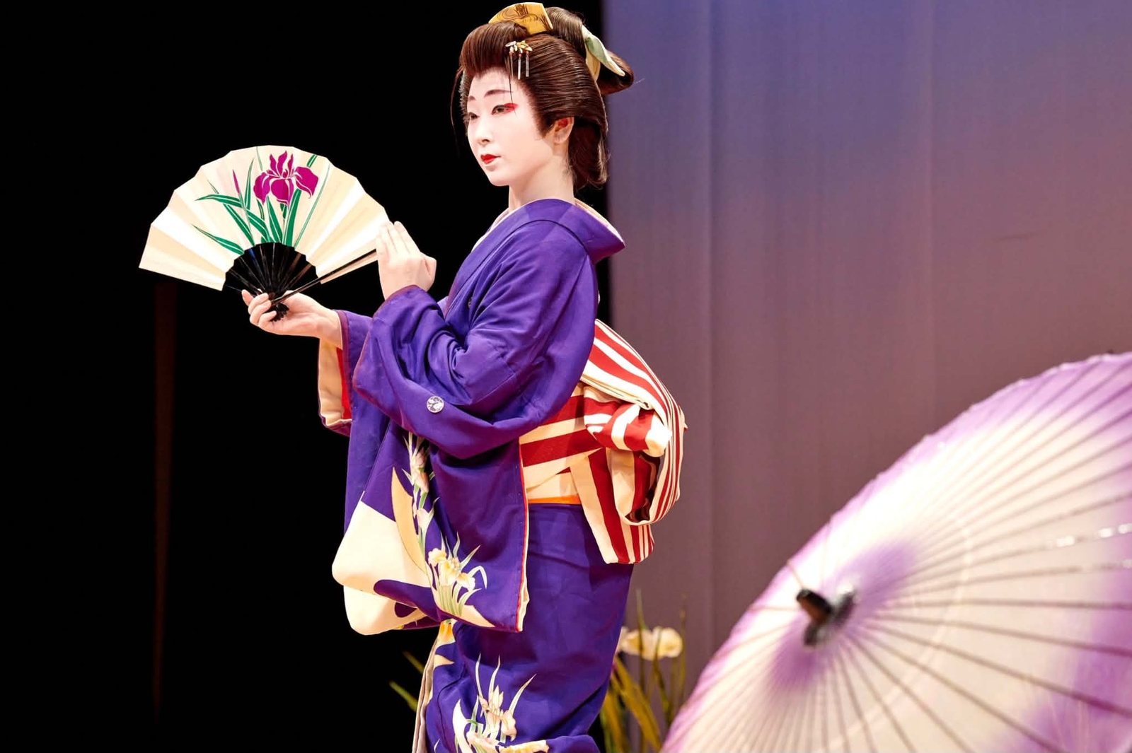 A DEN Tokyo dancer in a purple kimono, performing with a fan